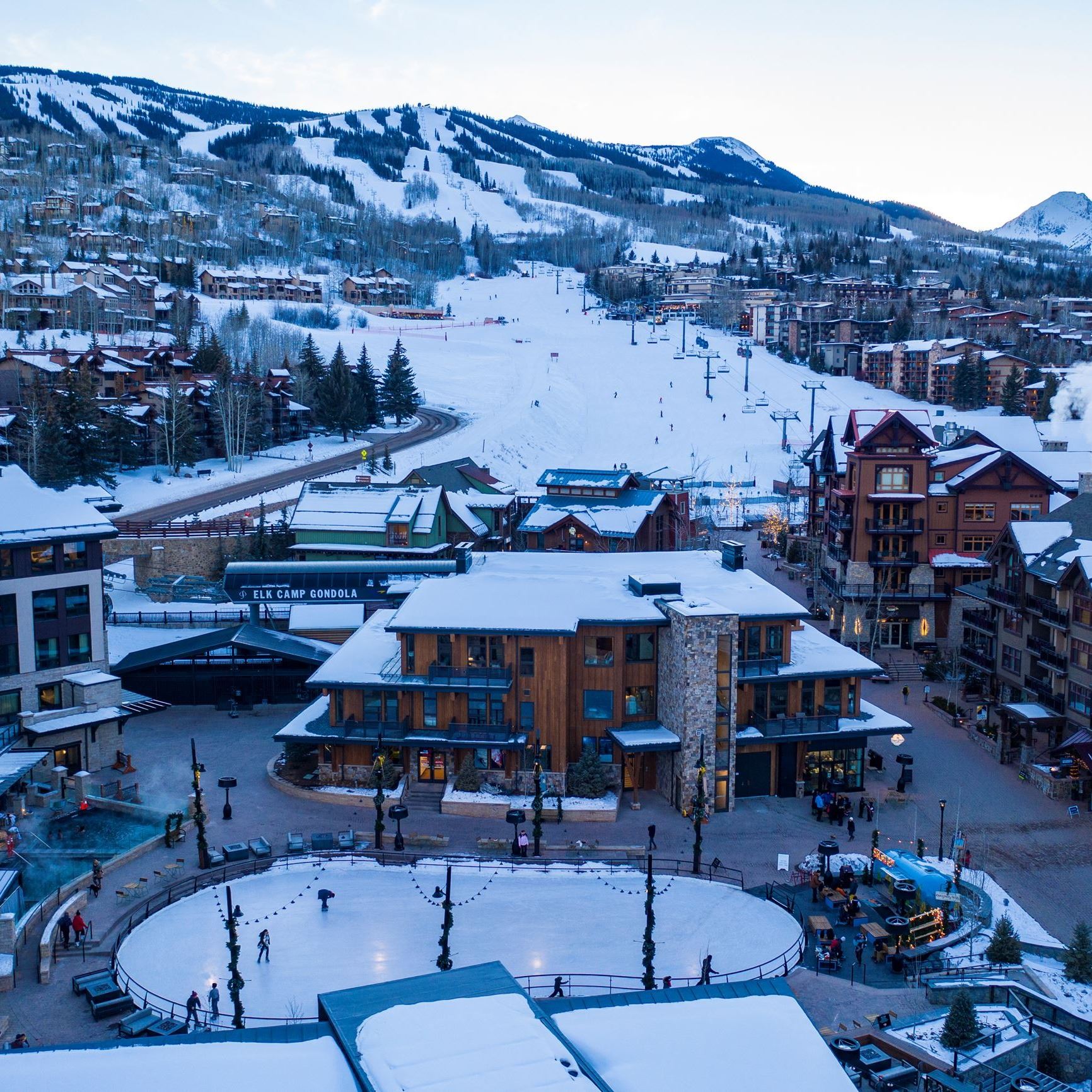 Drone photo looking at snowmass mountain from base village, overlooking ice rink in the winter time